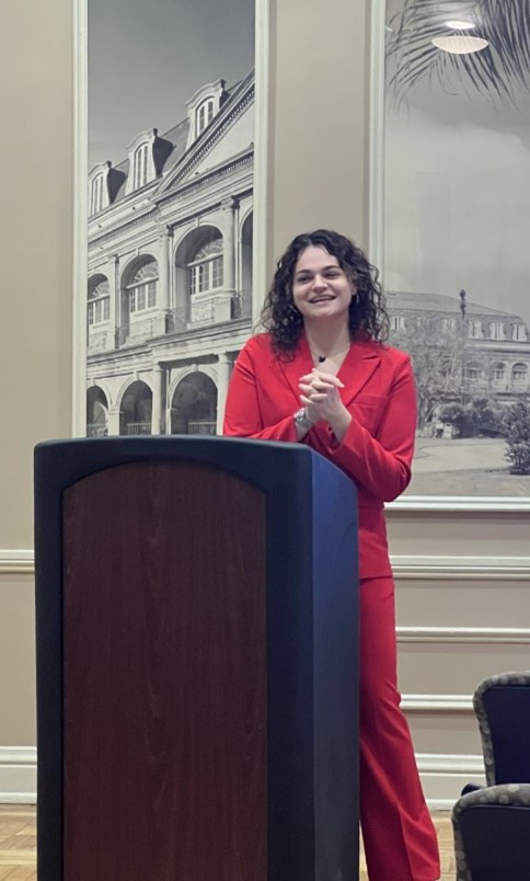 Woman in red suit presenting at a podium 