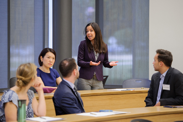 Woman in blue dress stands in classroom. 