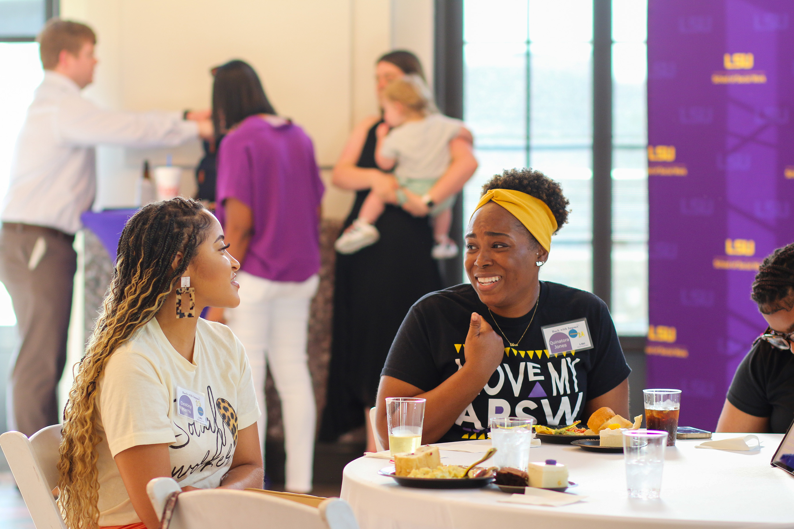 two women sitting at a table smiling and talking to each other