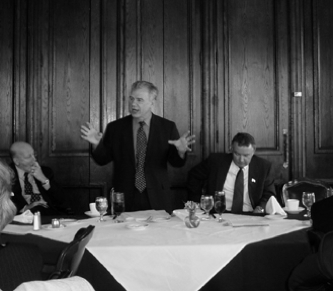 Image of man speaking to listeners in black and white